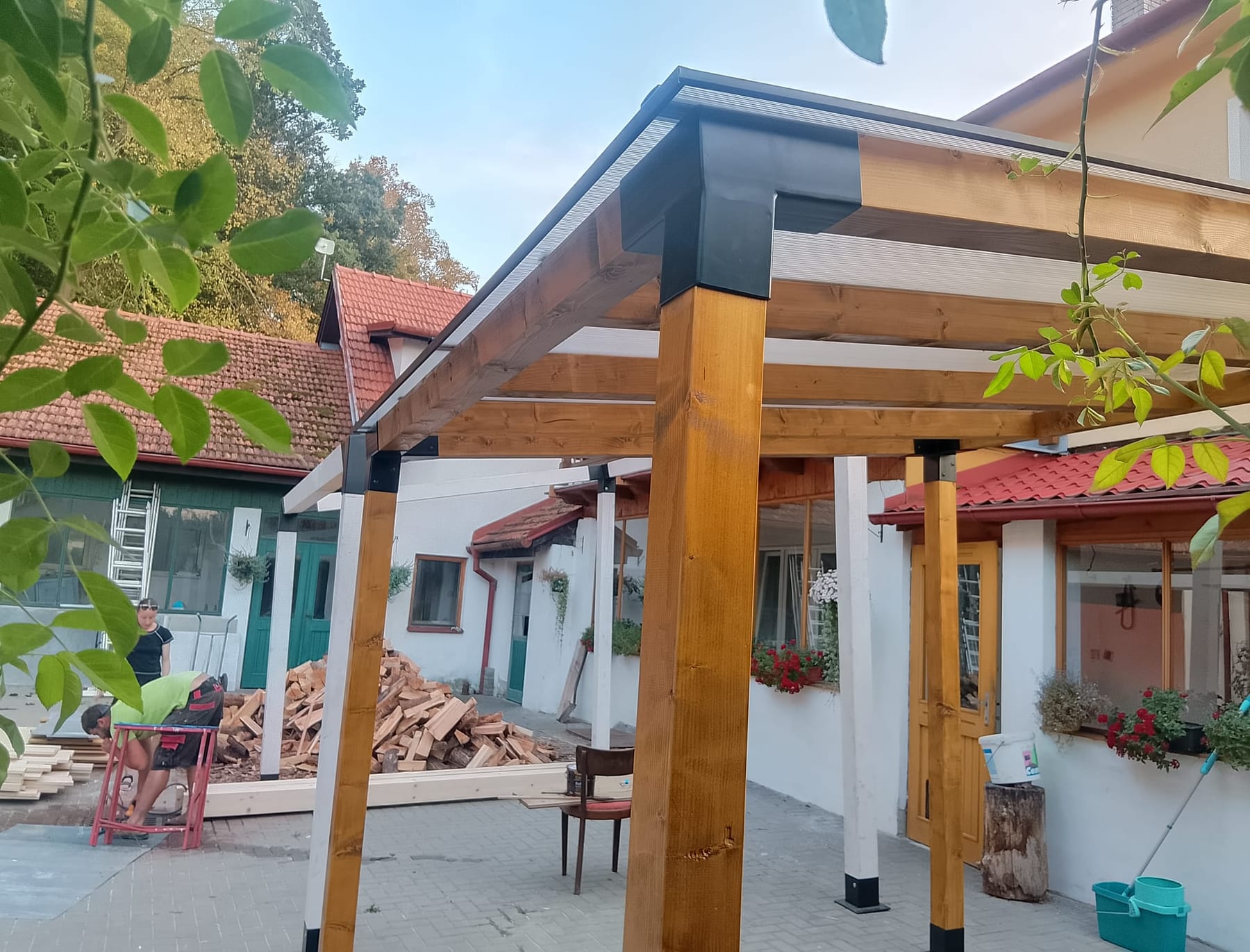 Montáž pergoly WMG na dvoře rodinného domu, tesař řeže hranol